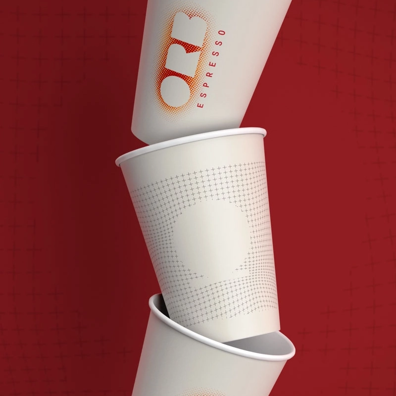 Closeup of three take-away coffee cups with the ORB Espresso logo, stacked on top of each other against a red background.