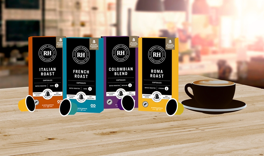 Four boxes of Robert Harris coffee capsules in different flavours: Italian Roast, French Roast, Colombian Blend, and Roma Roast with a cup of coffee in the background.